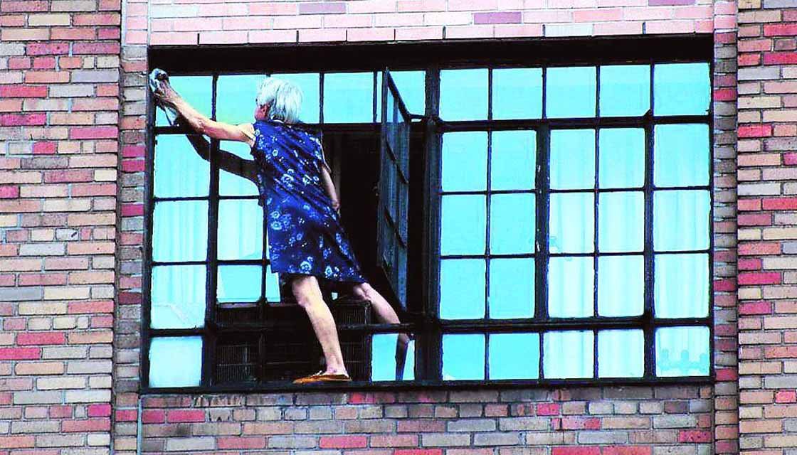 Женщина моет окно